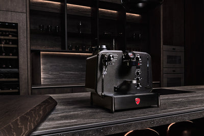 Barista M3 1926 Limited Edition i et mørkt luksuskøkken med vinkøleskab i baggrunden