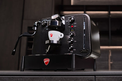 Hero-billede af Barista M3 1926, espresso hældes i en hvid Ducati-kop